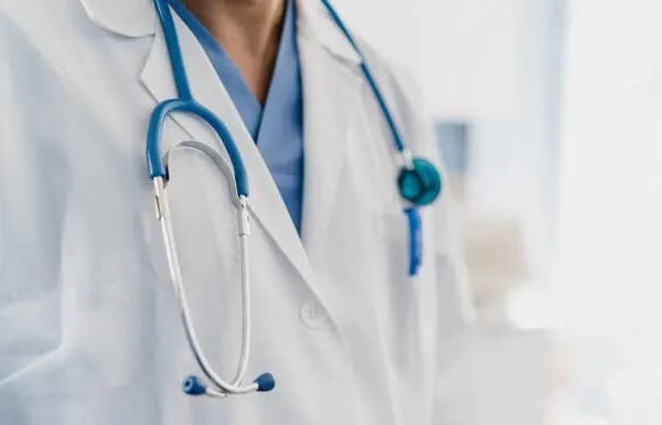 A doctor wearing scrubs and a stethoscope around their neck, standing in a clinical setting